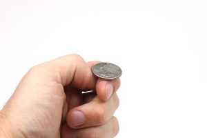 A hand holding a quarter just about to flip a coin.